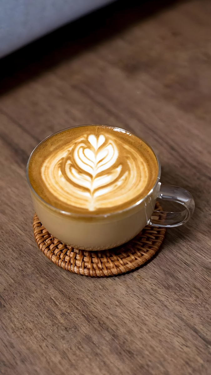 a cappuccino on a wooden table with a wicker coaster
